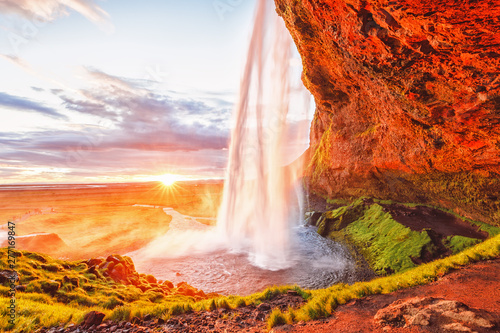 Seljalandsfoss Waterfall   Iceland. Iconic landmark and travel destination in Iceland. Breathtaking sunset landscape of famous and popular Icelandic waterfall Seljalandsfoss. Picturesque nature.