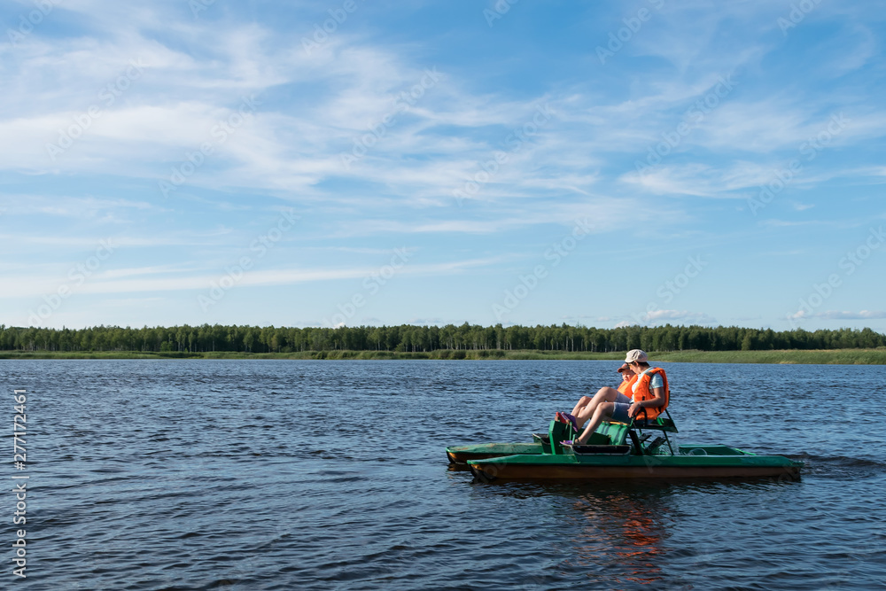 mom and son ride a catamaran on the lake in good weather on vacation, active vacation