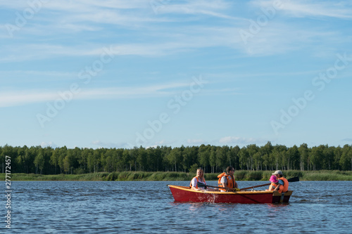 family rides a wooden boat on the lake in good weather on vacation, active holidays