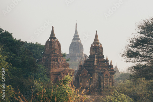 View over stupas and pagodas of ancient Bagan temple complex during sunrise golden hour in Myanmar
