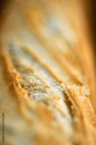Detailed macro close up shot of french bread baguette out of oven fresh warm cooked baked crunchy crust toast disposed in metallic oven professional special trays.