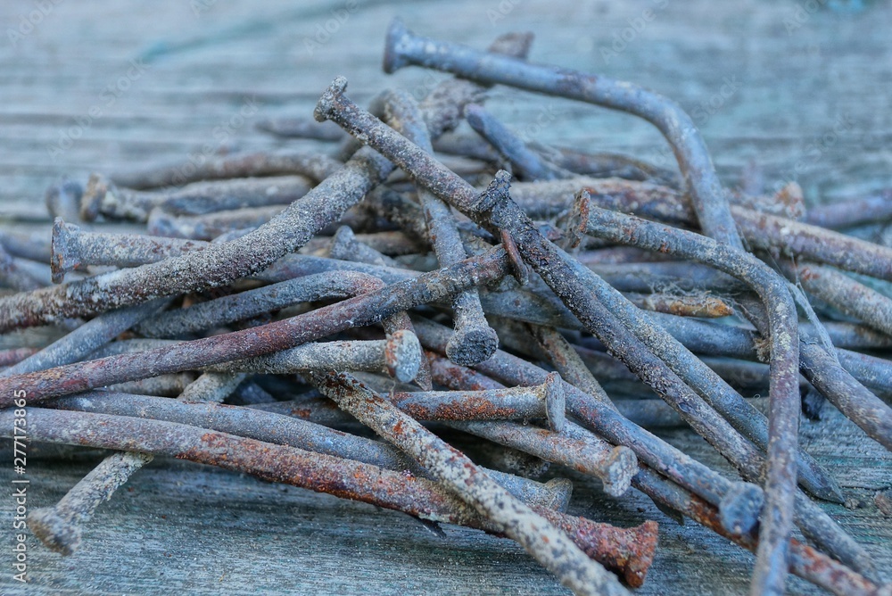 heap of old rusty nails lie on a gray wooden table heap of old rusty nails lie on a gray wooden table