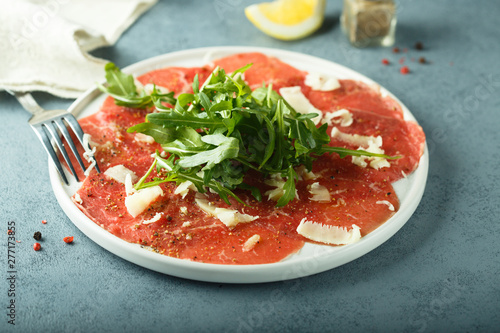 Homemade beef carpaccio with cheese and arugula