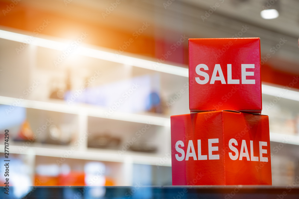 goods in stores and a red sign on sales discounts. mocap for text and concept of sales and trade in light industry. sales advertising in the store on the shelf. cardboard boxes with advertising about