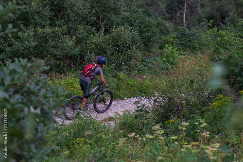 Cyclist in Red Riding the Bike on the Autumn Rocky Trail at Sunset. Extreme Sport and Enduro Biking Concept