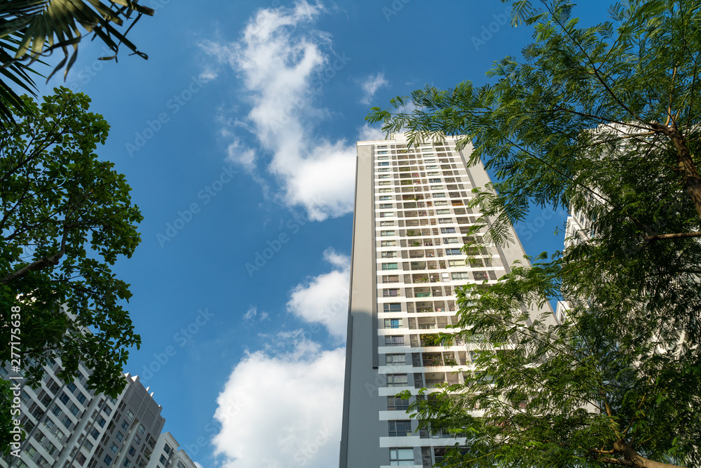 Modern condominium building with green leaves on foreground. Green city concept Modern condominium building with green leaves on foreground. Green city concept