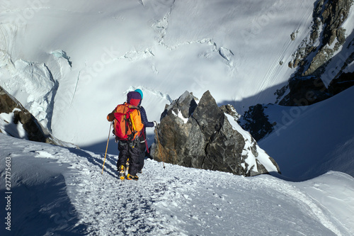 Tied climbers climbing mountain with snow field tied with a rope with ice axes and helmets