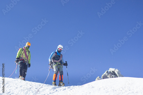 A group of mountaineers climbs to the top of a snow-capped mountain