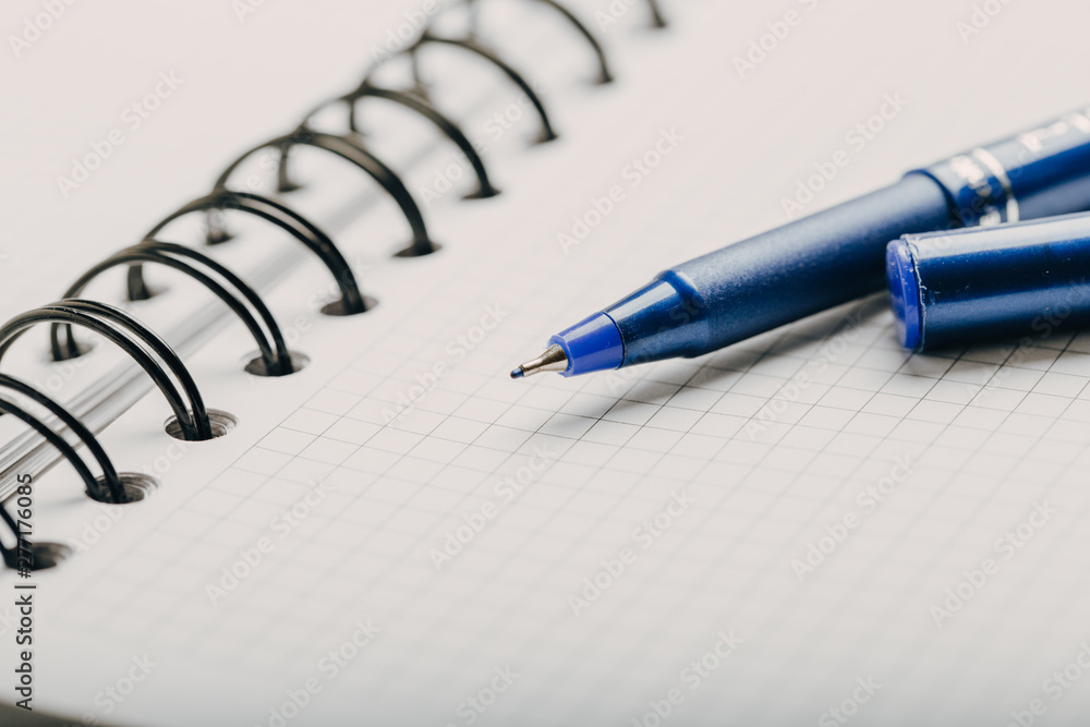 Opened notepad in a cage with an automatic plastic ballpoint pen close-up. toned Opened notepad in a cage with an automatic plastic ballpoint pen close-up. toned