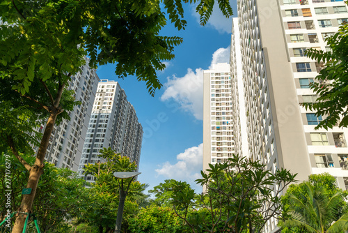 Modern condominium building with green leaves on foreground. Green city concept photo