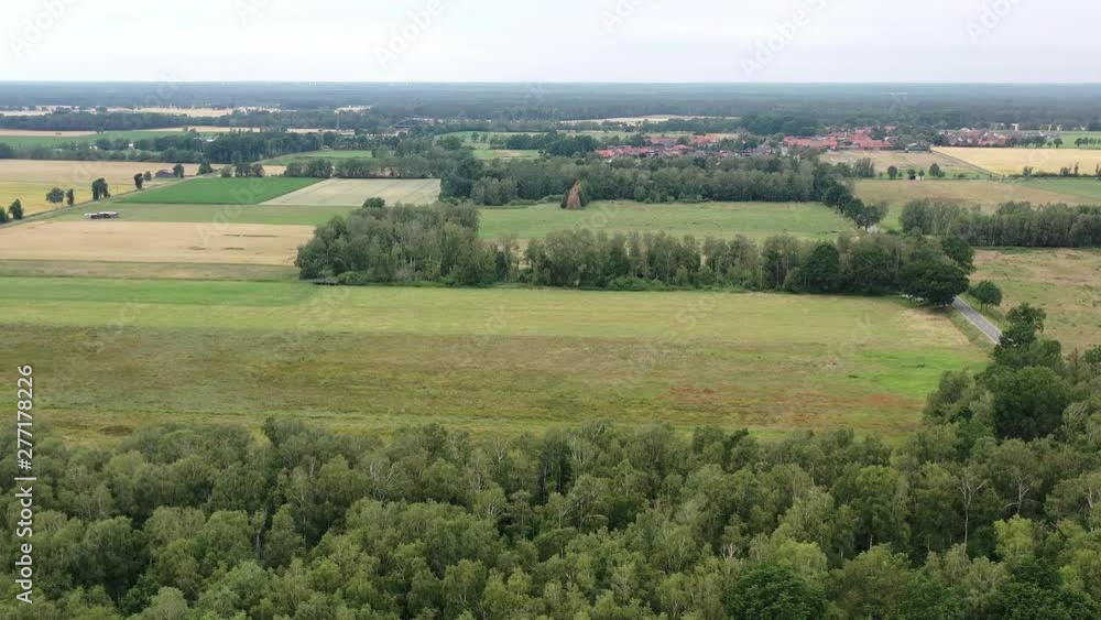 POV from the swivel with the drone over a forest and view of a small typical village in the north of Germany in the distance POV from the swivel with the drone over a forest and view of a small typical village in the north of Germany in the distance
