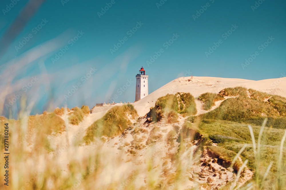 endless sand dunes with the old historic lighthouse Rubjerg Knude in bright summer light. Denmark