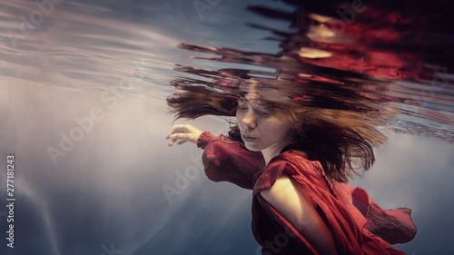 Girl in a red dress under water