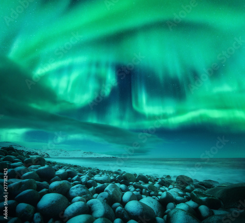 Aurora borealis above the snow covered mountain hill in europe. Beautiful Northern lights in winter. Night landscape with green polar lights and snowy mountains. Starry sky with aurora. Nature. Space © den-belitsky