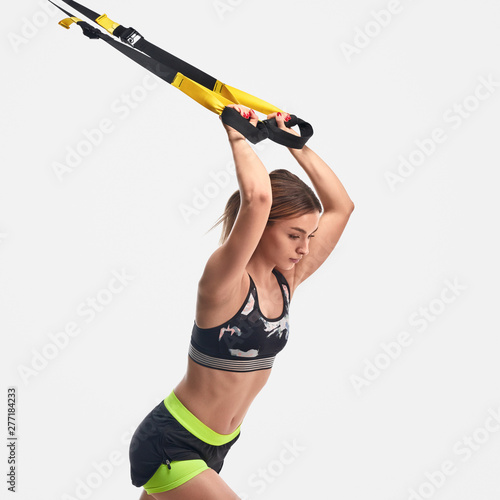 Strong woman pulling ropes during suspension training