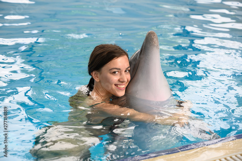 young beautiful brunette woman in a swimsuit swims and plays with a funny cute sea dolphin. Emotional rest in the water park. positive emotions  communication with marine mammals