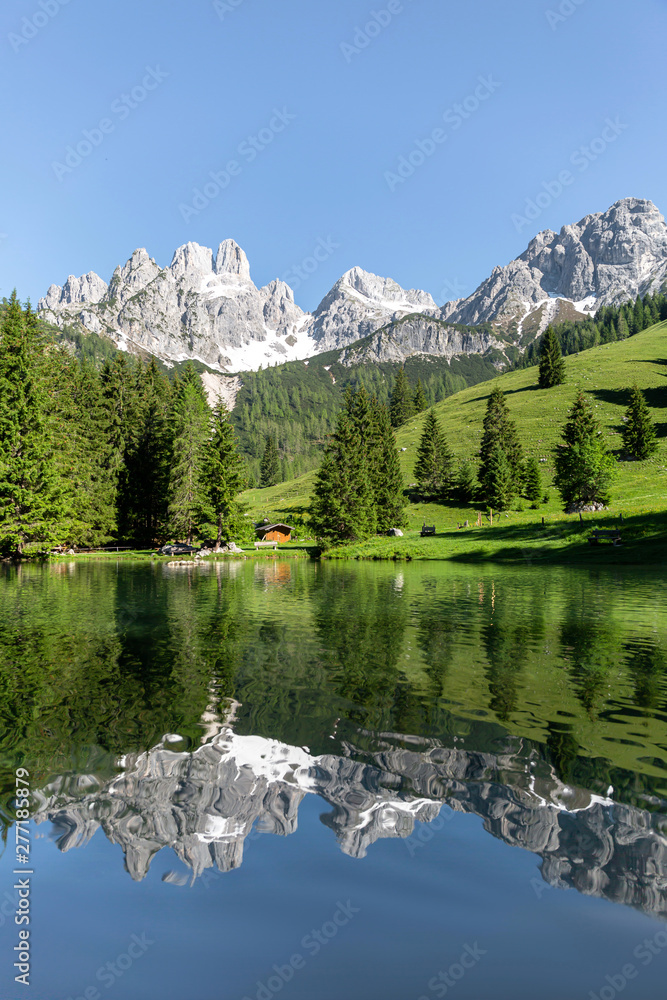 Picturesque summer landscape in the Alps with clear mountain lake and majestic mountain range in the background