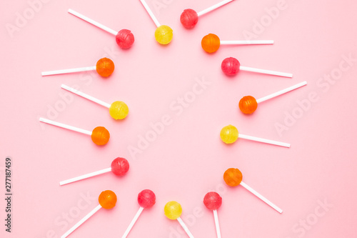 Pink, orange and yellow sweet candy lolipop on a pastel pink background © KatrinaEra