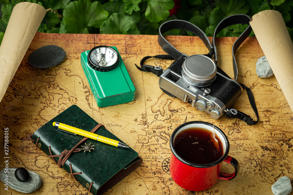 Vacation trip with a map next to a cup of tea and travel equipment, retro style - obrazy, fototapety, plakaty 