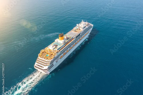 Obraz Statek wycieczkowy pływa w niebieskim morzu pozostawiając pióropusz na powierzchni morskiego krajobrazu. Widok z lotu ptaka Koncepcja podróży morskich, rejsy.