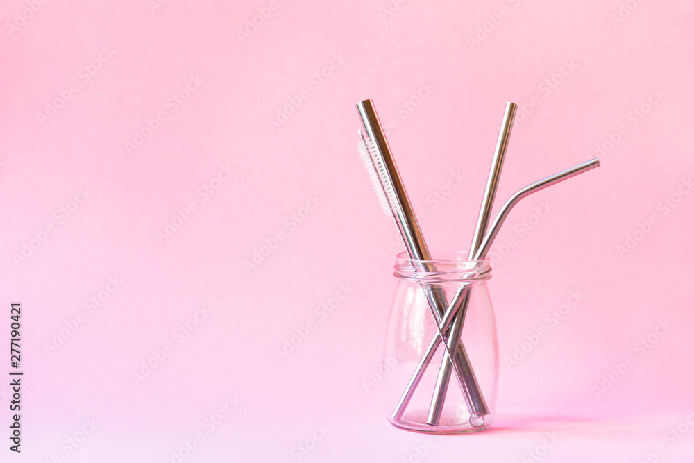 reusable stainless steel straws and cleaning brush in glass bottle on pink background, eco friendly lifestyle, copy space reusable stainless steel straws and cleaning brush in glass bottle on pink background, eco friendly lifestyle, copy space