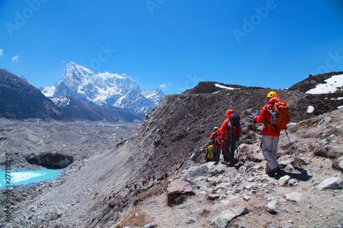 Group of tourists with backpacks descends down mountain trail to lake during a way to Everest base camp. Nepal.