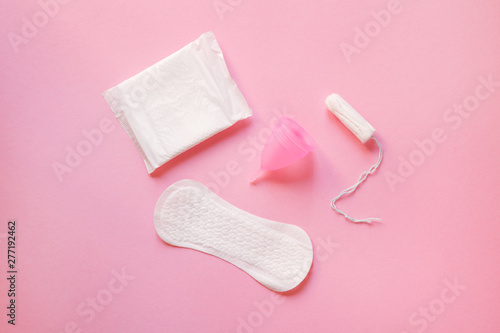 women intimate hygiene products - sanitary pads, menstrual cup and tampon isolated on pastel pink background, top view, flat lay