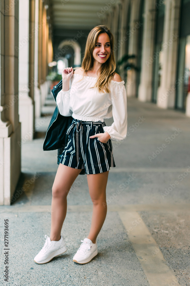 Portrait of young happy smiling beautiful elegant woman in black dress walking at city streets. Portrait of young happy smiling beautiful elegant woman in black dress walking at city streets.