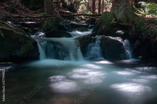 Fototapeta Naklejka Na Ścianę i Meble -  Blurred motion of water flowing through river rocks.