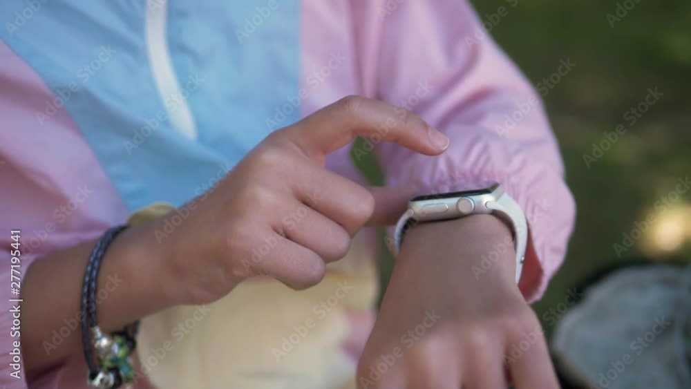 Kid Using Smartwatch or Smart Watch in park sitting on grass, Child in garden with airpods headphones dictate audio message with voice recognition Kid Using Smartwatch or Smart Watch in park sitting on grass, Child in garden with airpods headphones dictate audio message with voice recognition