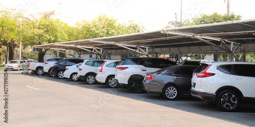 Closeup of rear, back side of white car with other cars parking in parking lot under roof in bright sunny day. 