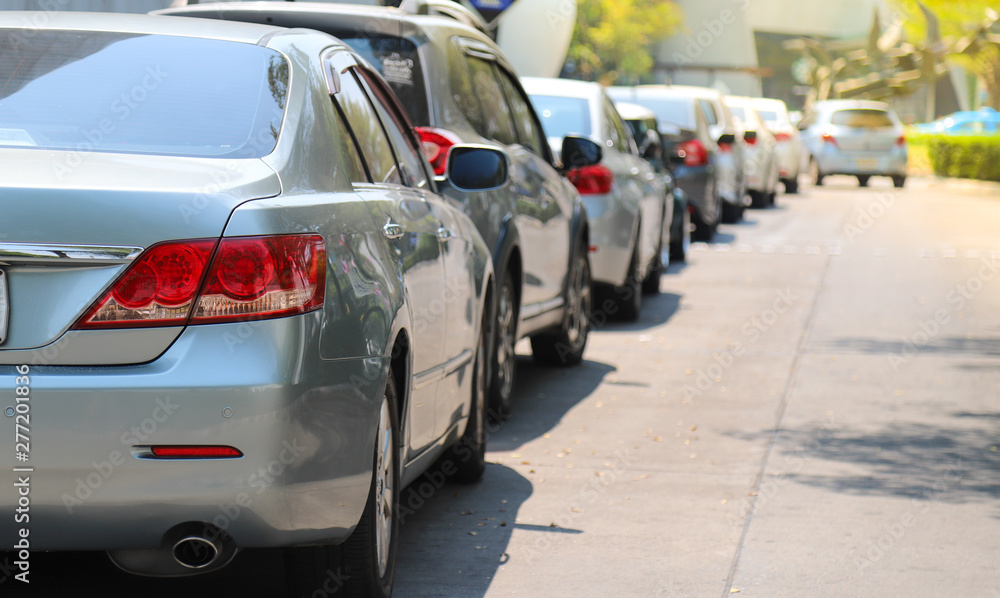 Closeup of rear or back side of green blue car with  other cars parking in outdoor parking area beside the street in bright sunny day.