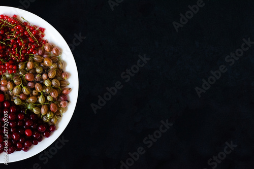 Juicy ripe berries in a plate on a black background. Berry pizza. Sector of berries on a plate. Ripe fresh berries on a black background.