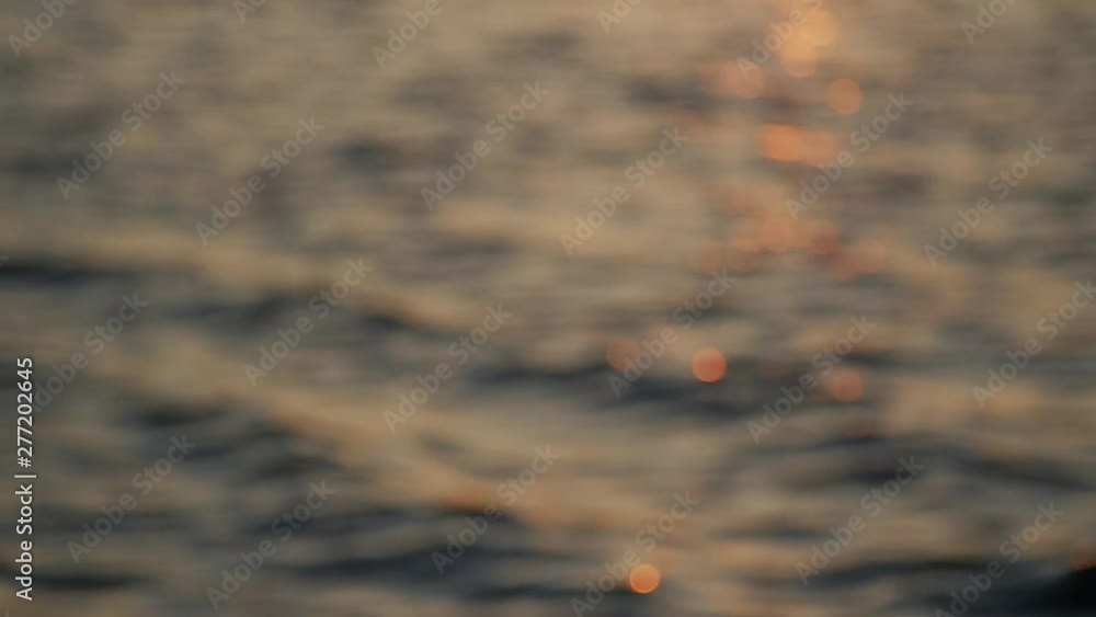 Out of focus, light sun beam reflection on calm water surface in evening, golden hour, slow motion. Out of focus, light sun beam reflection on calm water surface in evening, golden hour, slow motion.