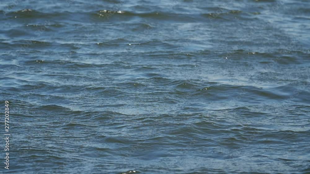 Blue lake water surface close up. Soft waves on the water surface. Blue deep water. Slow motion. Blue lake water surface close up. Soft waves on the water surface. Blue deep water. Slow motion.