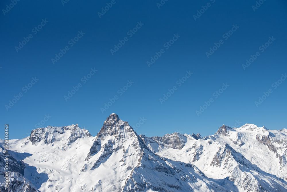 Winter mountains with snow and blue sky in nice sun day. Ski resort and sport concept. Caucasus Mountains, region Dombay. View from the top of Musa Achitara, copy space, moc up