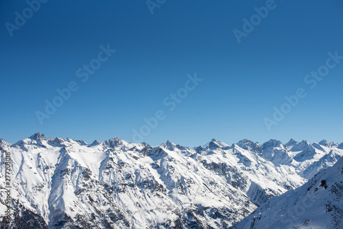 Winter mountains with snow and blue sky in nice sun day. Ski resort, sport concept. Caucasus Mountains, region Dombay. Wallpaper, banner, background, deep blue color. copy space, moc up