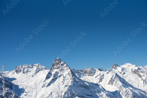 Winter mountains with snow and blue sky in nice sun day. Ski resort and sport concept. Caucasus Mountains, region Dombay. View from the top of Musa Achitara, copy space, moc up © Alla Bacherikova