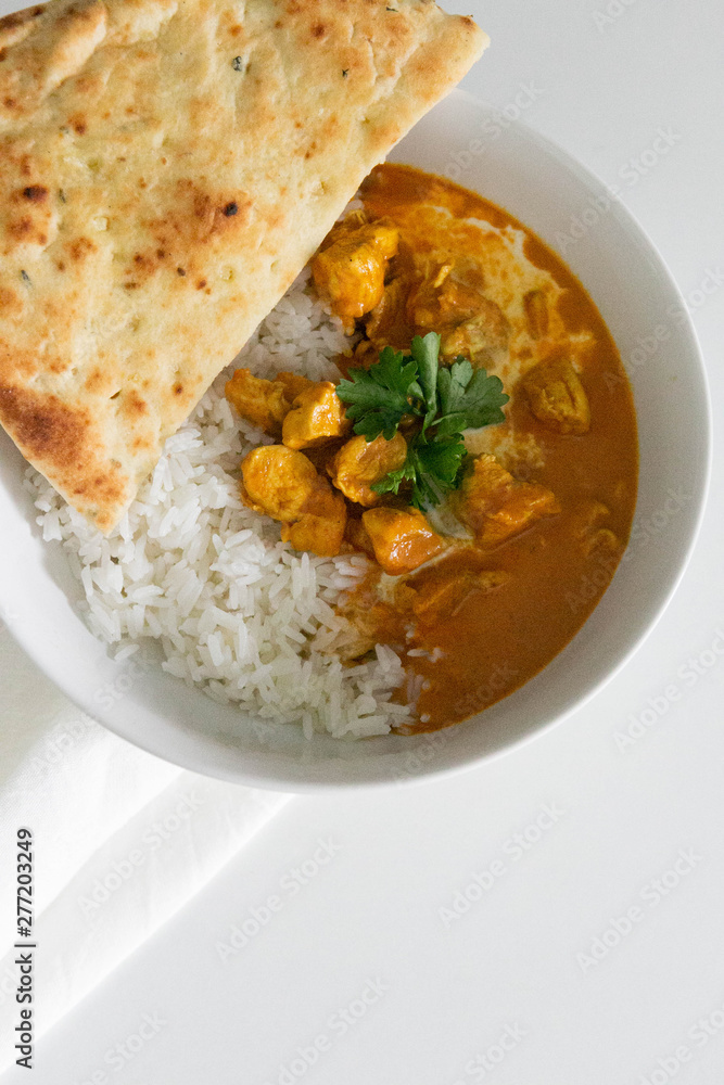 Bowl of Indian Butter Chicken with Jasmine Rice, Homemade Naan, and Cilantro, White Background, Closeup Bowl of Indian Butter Chicken with Jasmine Rice, Homemade Naan, and Cilantro, White Background, Closeup
