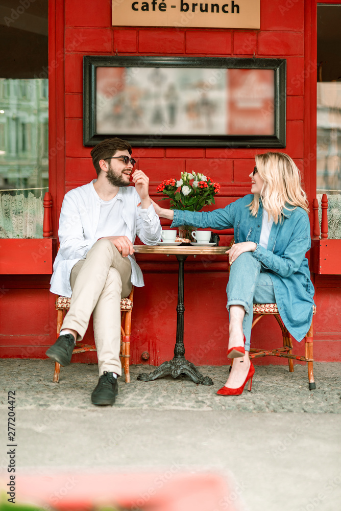 Happy beautiful couple is sitting in outdoor cafe - obrazy, fototapety, plakaty 