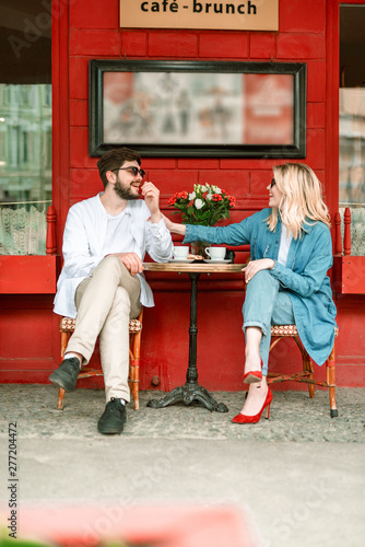 Valokuvatapetti Happy beautiful couple is sitting in outdoor cafe