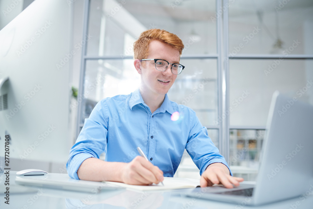 Fototapeta premium Young successful designer looking at curious online stuff on laptop display