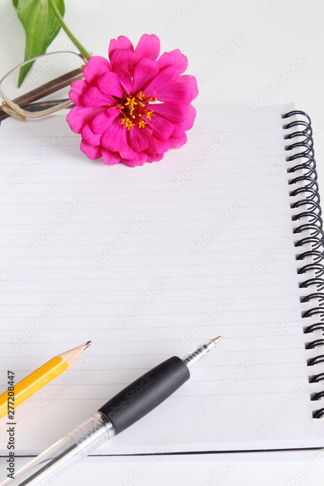 blank notepad with flower,pencil,pen on a white background top view blank notepad with flower,pencil,pen on a white background top view