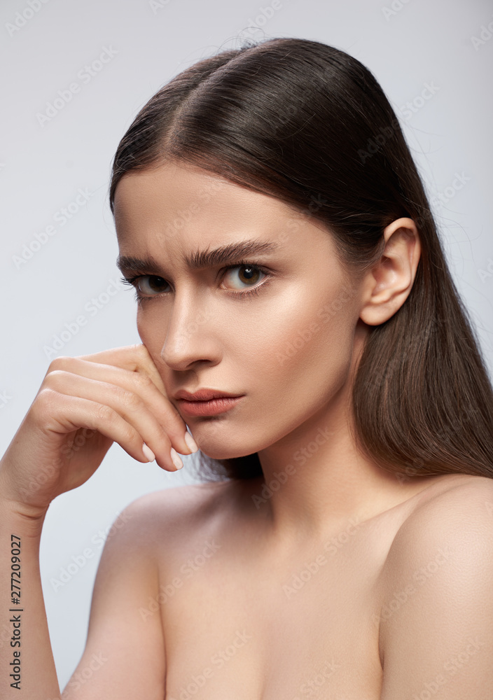 Upset woman standing against light gray background in studio Upset woman standing against light gray background in studio