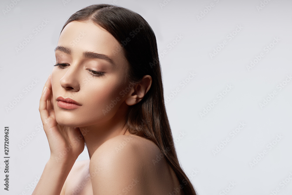 Charming young lady with natural makeup keeping hand near head Charming young lady with natural makeup keeping hand near head