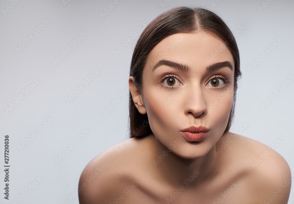Cheerful young lady with natural makeup pouting lips Cheerful young lady with natural makeup pouting lips