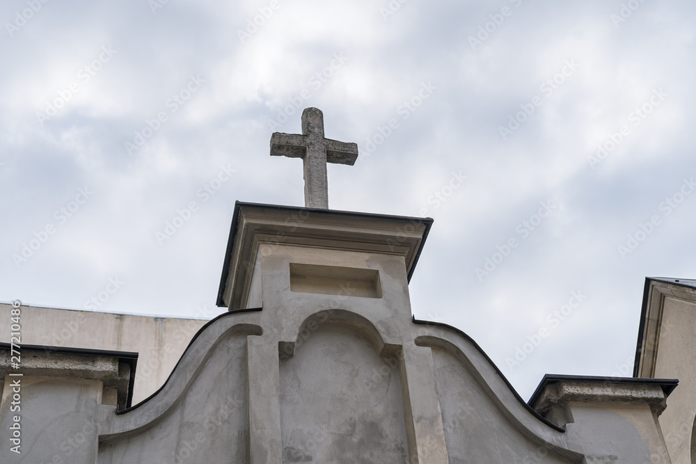 Catholic cross on a church against cloudy sky.