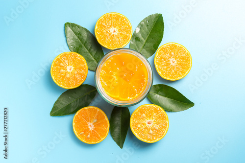 Glass of orange juice with sliced orange fruits with leaves on blue background, flat design