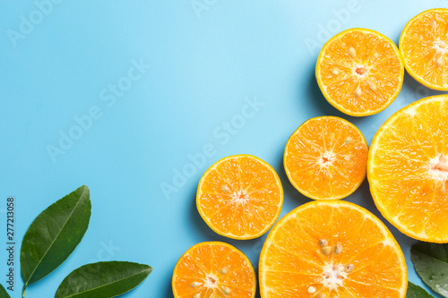 Sliced orange fruits with leaves on blue background, flat design