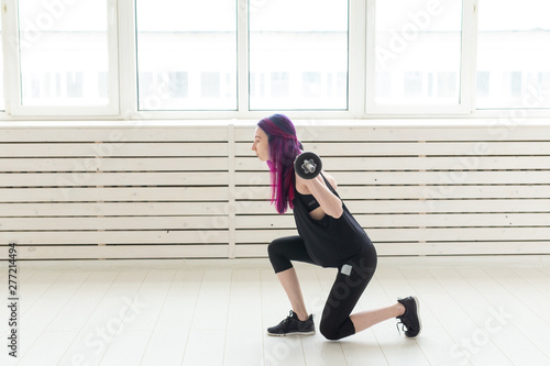 Fitness, sport, people concept - young woman in sport suit is squatting with bar